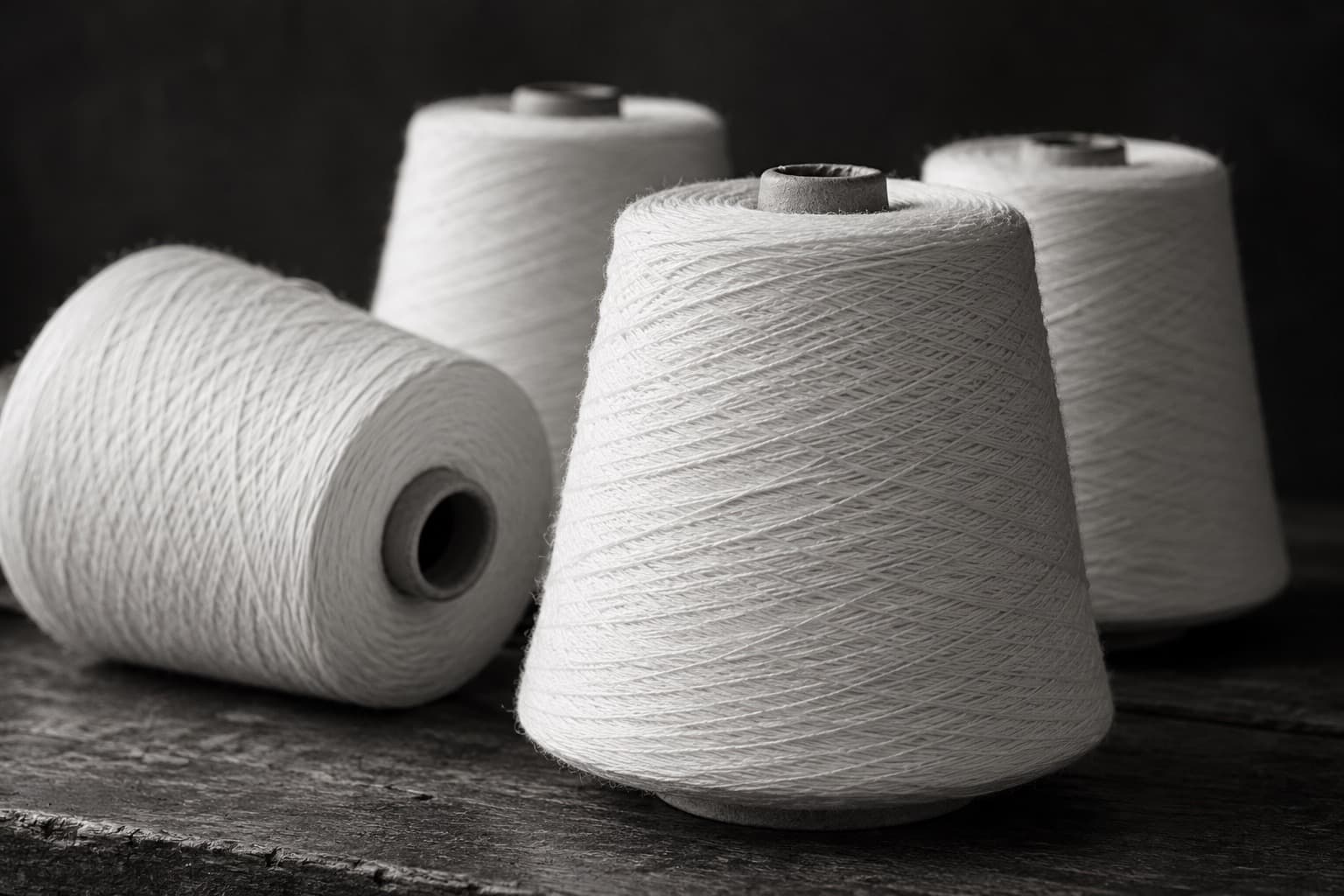 Cones of white cotton yarn on a wooden table